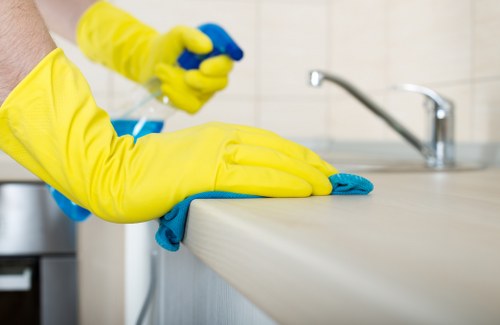 Local cleaner treating stains on a corner sofa in SW11